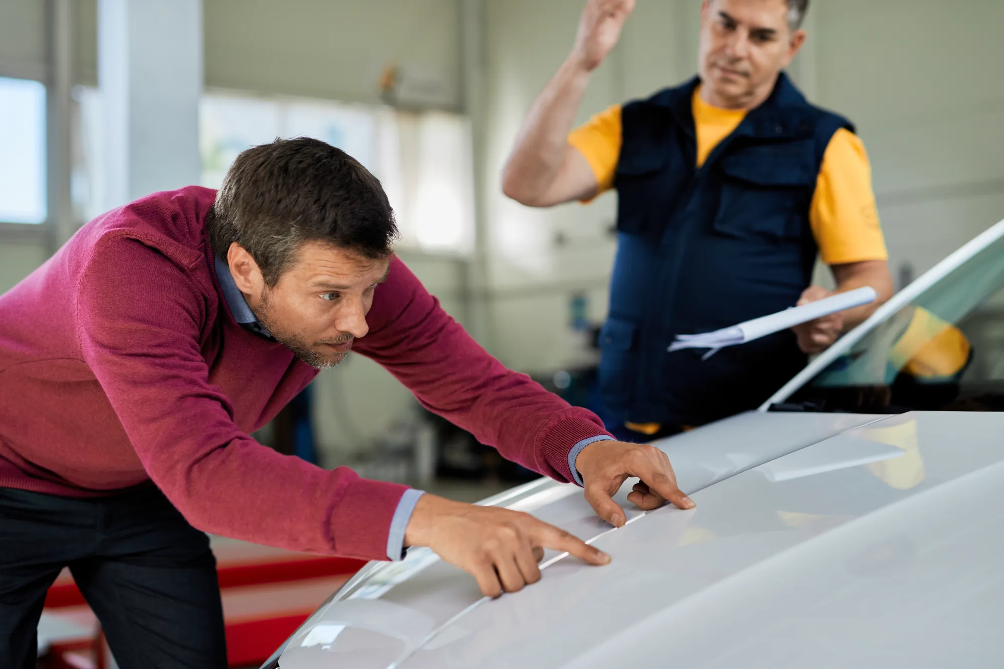 Customer examining a repaired car hood at a Dent Master Global shop